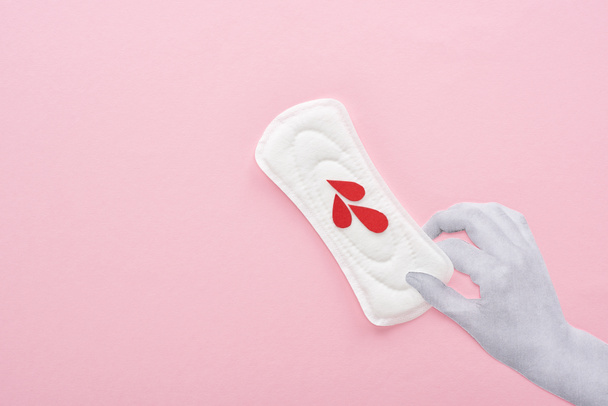 vista ritagliata di mano tenendo tovagliolo sanitario bianco con gocce di sangue su sfondo rosa
 - Foto, immagini
