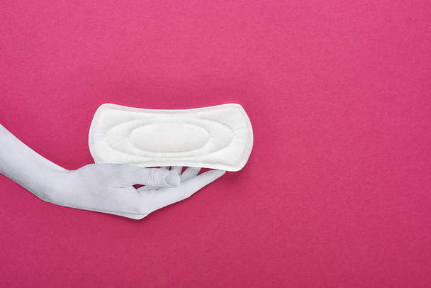 top view of paper cut white hand and white sanitary napkin on purple background - Foto, imagen