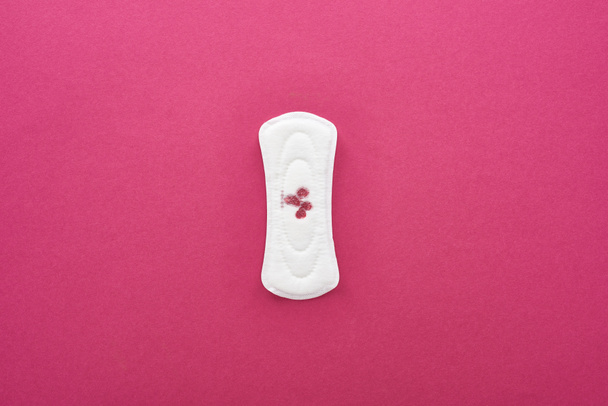 top view of white sanitary napkin with blood on purple background - Zdjęcie, obraz