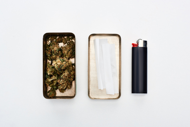 płaskie lay z metalowym pudełku z pąki marihuany i toczenia papieru w pobliżu lżejsze - Zdjęcie, obraz