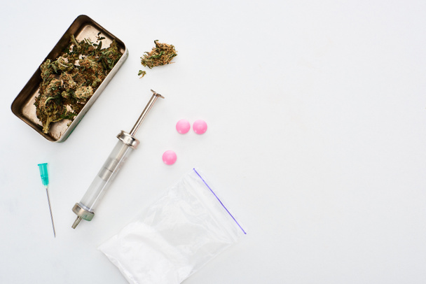 top view of marijuana buds, heroin, lsd and syringe on white background - Photo, Image