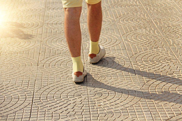 Los pies de los hombres en zapatos ligeros y calcetines amarillos van por el camino. Th
 - Foto, imagen