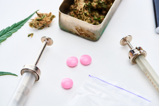 vista da vicino di germogli di marijuana, siringhe vicino all'estasi rosa ed eroina su sfondo bianco
 - Foto, immagini