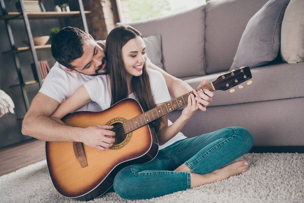 Portrait of his he her she two nice-looking attractive lovely tender cheerful cheery positive people spending day daydream sitting on floor playing melody at home house apartment indoors - Fotó, kép