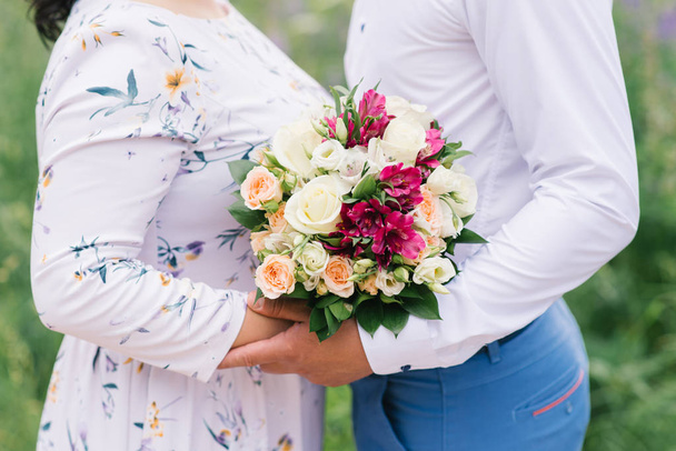 Een romantische date van een man en een meisje, een close-up van een boeket bloemen, een geschenk aan een meisje. Bruid en bruidegom. Bruiloft boeket - Foto, afbeelding