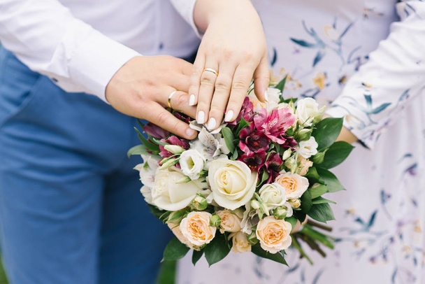 Ręce panny młodej i pana młodego z obrączki leżą na Bukiet ślubny z jasnych kwiatów. Małżeństwo od wielu lat - Zdjęcie, obraz