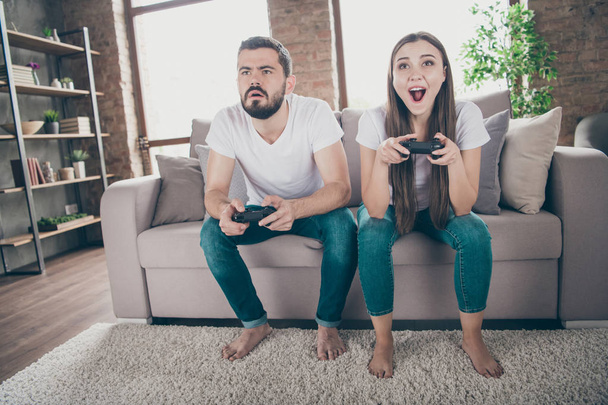 Photo of funny homey mood pair sitting sofa indoors playing video games excited who wins - Valokuva, kuva