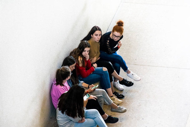 Берлін, Німеччина-26 вересня 2018: збільшеною в, вниз перспектива групи дівчаток грають на своїх смартфонах, сидячи в кам'яну лавку на острові Берлінський музей, музей Неес - Фото, зображення