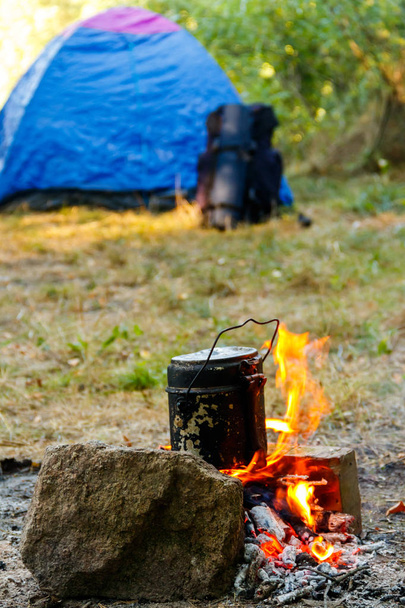 Kochen am Lagerfeuer im Zelten. Zelt und Rucksack im Hintergrund - Foto, Bild