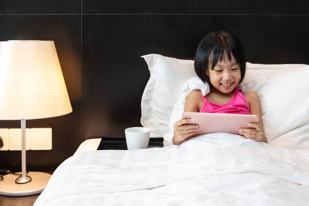 Asiatico piccolo cinese ragazza giocare tablet in letto
 - Foto, immagini