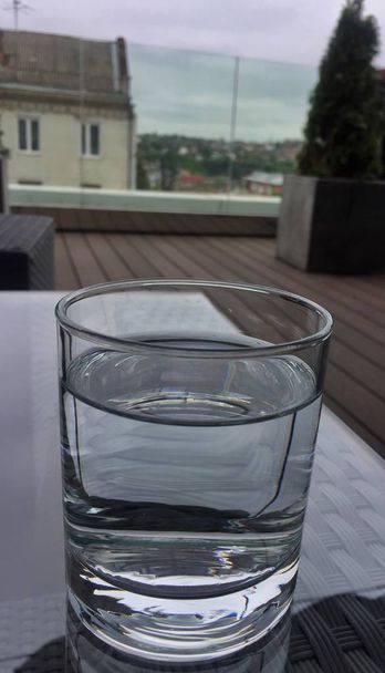 Склянка води на скляному столі
 - Фото, зображення