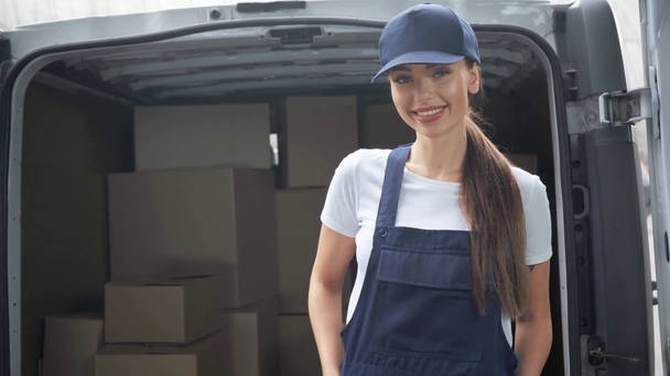 doručovací žena stojící s rukama v kapsách blízko vozu s balíky  - Záběry, video