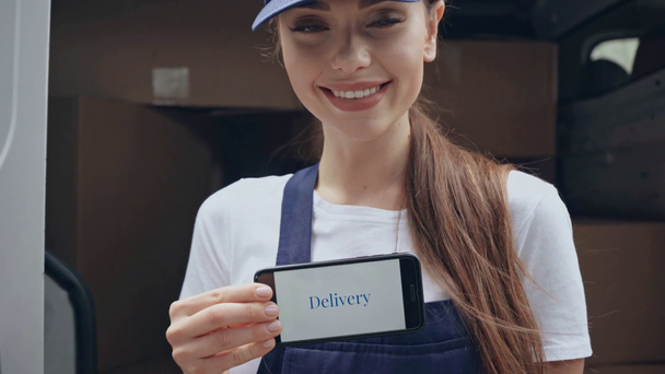 happy woman holding smartphone with delivery lettering - Footage, Video