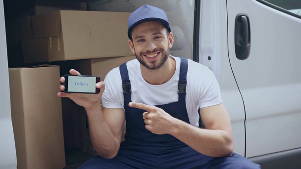 muž ukazovací prstem na smartphone s dodacími písmeny u auta s krabic  - Záběry, video