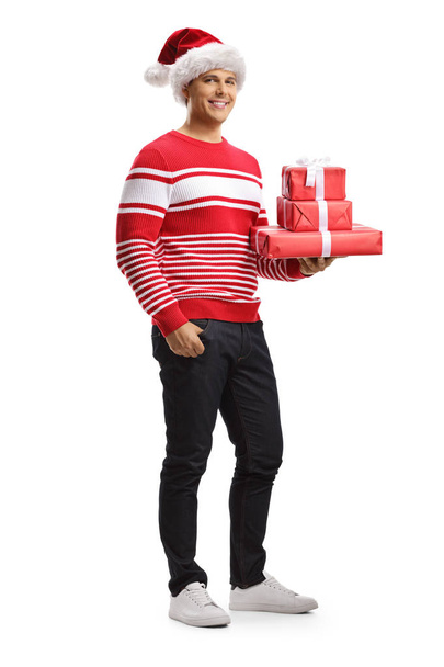 Young man with a santa claus hat holding christmas gifts - 写真・画像