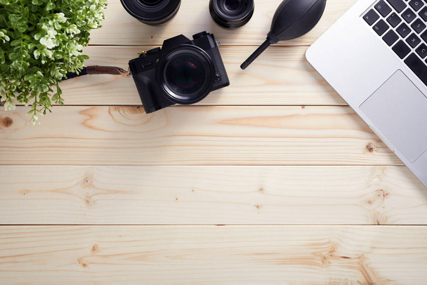 Top view of photographer desk with latptop, camera and lenses with copy space. Flat lay shot on wooden background. - Photo, image