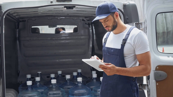 Człowiek dostawy wody za pomocą cyfrowego tabletu i liczenia butelek w samochodzie  - Materiał filmowy, wideo