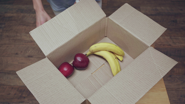 vista recortada de la mujer tomando frutas de la caja de cartón
 - Imágenes, Vídeo