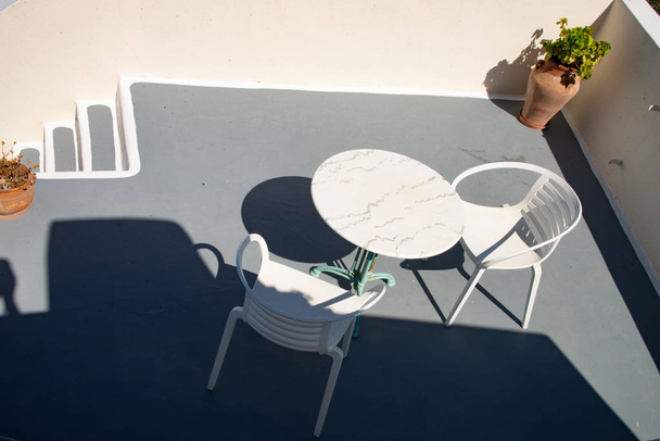 Witte stoelen en tafels op het typische Griekse terras. Voor ontbijt of koffiepauze op het eiland Santorini in Europa. - Foto, afbeelding