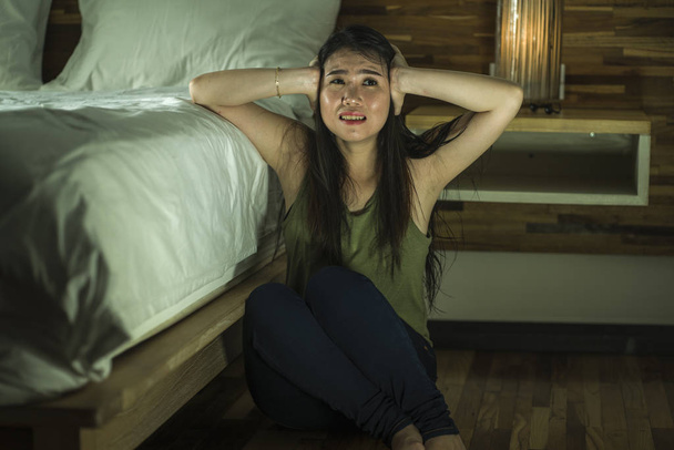young depressed and sad Asian Korean woman sitting on floor at bedroom next to bed suffering depression problem and anxiety crisis feeling desperate - Photo, Image