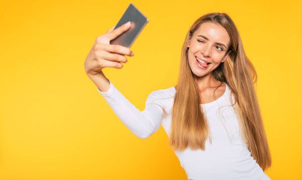Blonde young attractive woman with smartphone. Selfie photo on cellphone. Happy picture. - Photo, image