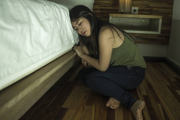 young depressed and sad Asian Korean woman sitting on floor at bedroom next to bed suffering depression problem and anxiety crisis feeling desperate - Foto, Imagen