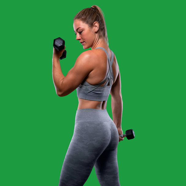 Potente ejercicio femenino atractivo muscular con pesas, brazos tonificados, bíceps, utilizando mancuernas para tonificar y fortalecer el brazo de fitness
 - Foto, imagen