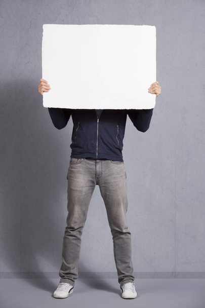 Man holding blank panel covering his face. - Фото, зображення