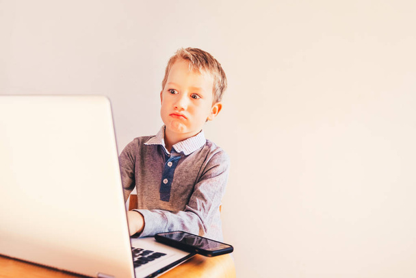 Child with very expressive face in front of a laptop with angry  - Photo, Image