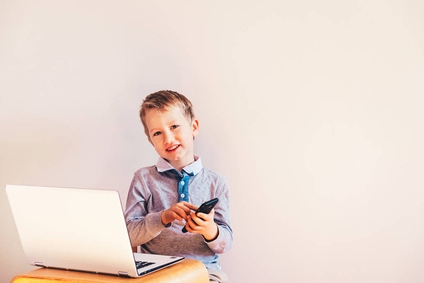 Щаслива смішна дитина працює виконавчим директором зі своїм ноутбуком і привіт
 - Фото, зображення