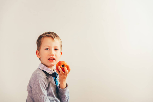 Niño feliz mordiendo una manzana sabrosa, aislado sobre fondo blanco f
 - Foto, imagen