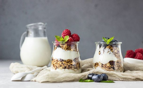 Jars with tasty parfait made of granola, berries and yogurt on stone grey table. Copy space. - Photo, Image