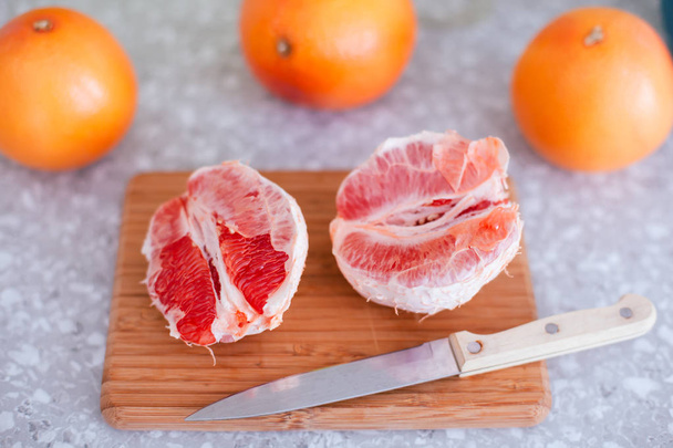 Ripe grapefruits and knife on cutting board.  - Valokuva, kuva