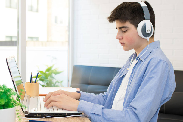 student v pubertě s počítačem a sluchátky na ploše - Fotografie, Obrázek