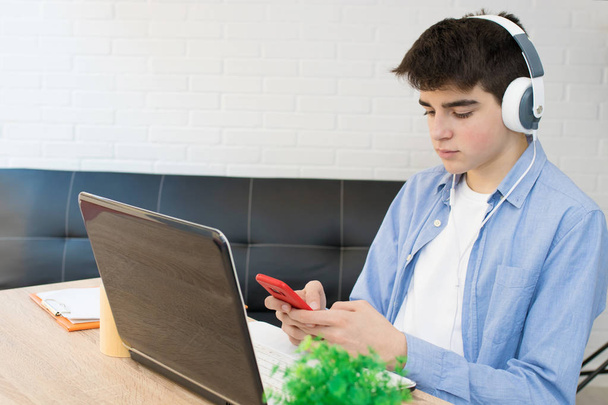 студент с компьютером, телефоном и наушниками на рабочем столе
 - Фото, изображение
