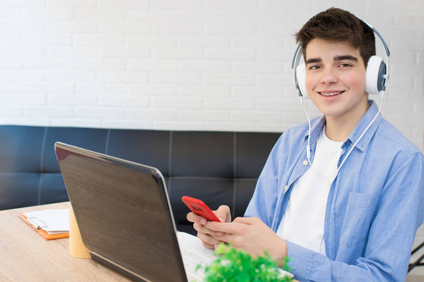 estudiante con computadora, teléfono y auriculares en el escritorio
 - Foto, Imagen