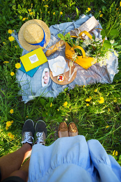 una pareja cariñosa, un picnic en la naturaleza, una alfombra en la que se encuentra comida-queso, baguette, pastel, fresa
 - Foto, Imagen