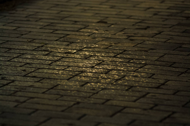 Hintergrund oder Textur von einer gebrochenen und gleichen Fliese mit Lichtflecken und Tropfen. Steinblöcke auf dem Bürgersteig. - Foto, Bild