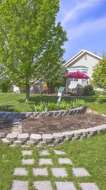 緑豊かな木々と装飾的なコンクリートの石と家の垂直美しい草の庭 - 写真・画像