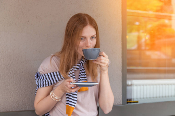 Городской туризм. Молодая очаровательная женщина, сидящая одна в кафе с чашкой кофе, расслабляясь в кафе
 - Фото, изображение