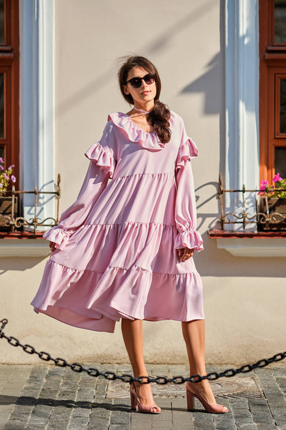 Outdoor urban portrait of young beautiful stylish girl in oversized pink dress - Фото, изображение