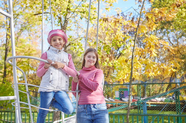 Girl with Down syndrome and little girl in autumn park. - Foto, imagen