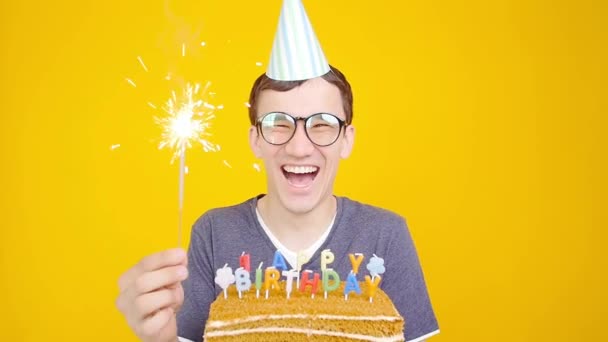 Boldog születésnapot koncepció. Fiatal vicces ember süteménnyel o egy narancs háttér - Felvétel, videó