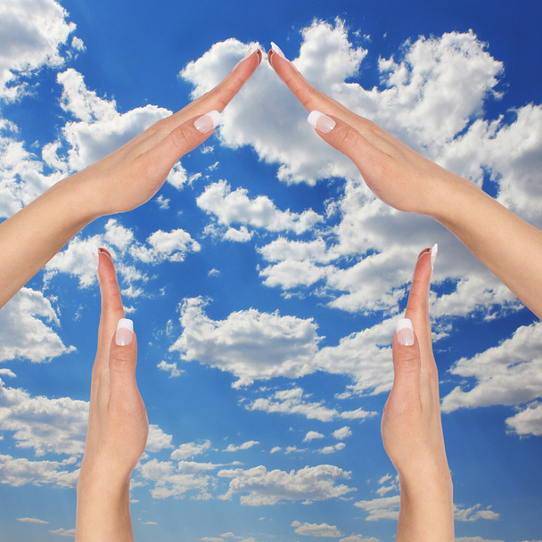 House made of female hands over blue sky with clouds. concept symbol home - Fotó, kép