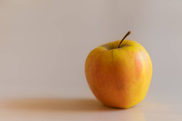 one ripe yellow orange apple on the table. - Photo, Image