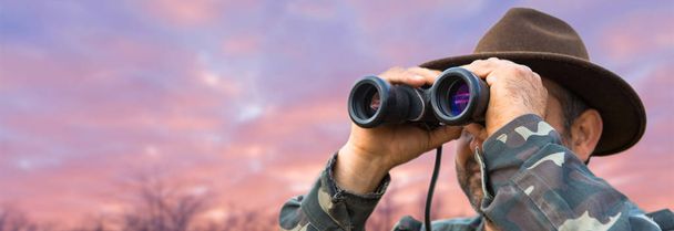 man looking through binoculars at sunset - Photo, Image