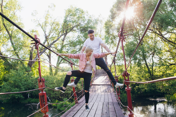 Couple guy and girl on the bridge over the river fooling around - 写真・画像
