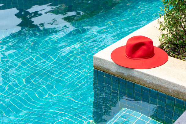 Sombrero rojo en la piscina de agua azul  - Foto, Imagen