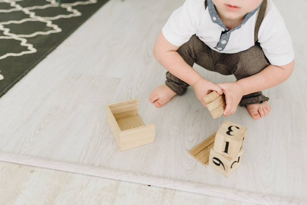 Söpö pieni poika leikkii puisilla tiilillä valkoisella lattialla
 - Valokuva, kuva