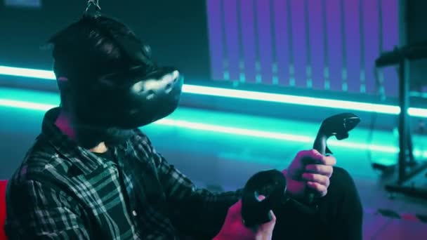 Brodaty człowiek gra w VR za pomocą nowoczesnego zestawu słuchawkowego wirtualnej rzeczywistości z gamepad, pilot zdalnego sterowania - Materiał filmowy, wideo